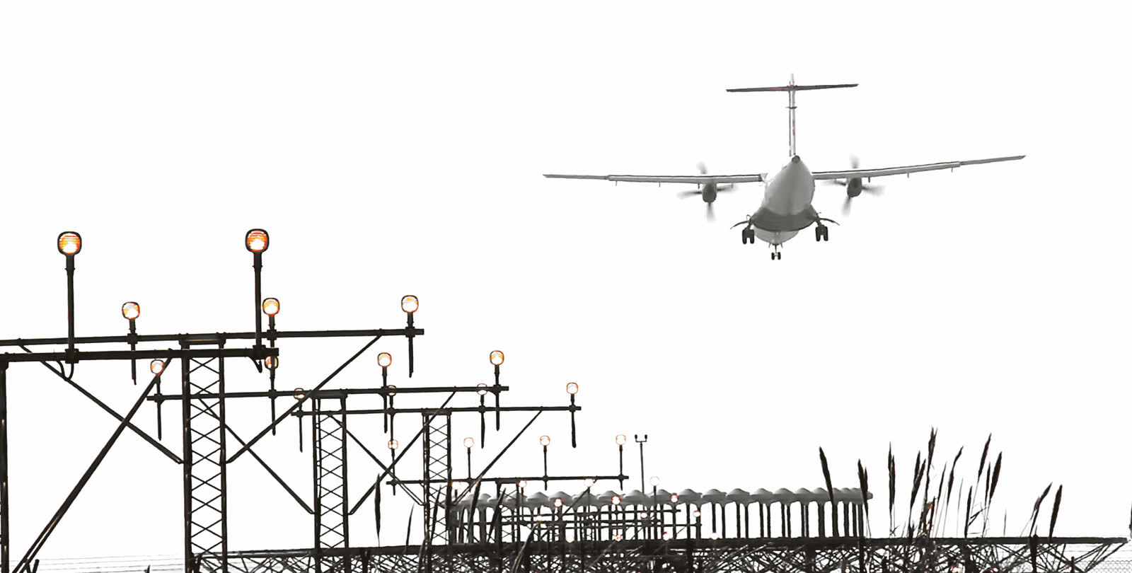 A regional turboprop on final approach above a row of runway approach lights